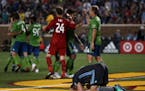Minnesota United defender Brent Kallman (14) falls to the ground in despair as the Seattle Sounders celebrate their stunning come from behind victory.
