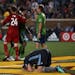 Minnesota United defender Brent Kallman (14) falls to the ground in despair as the Seattle Sounders celebrate their stunning come from behind victory.