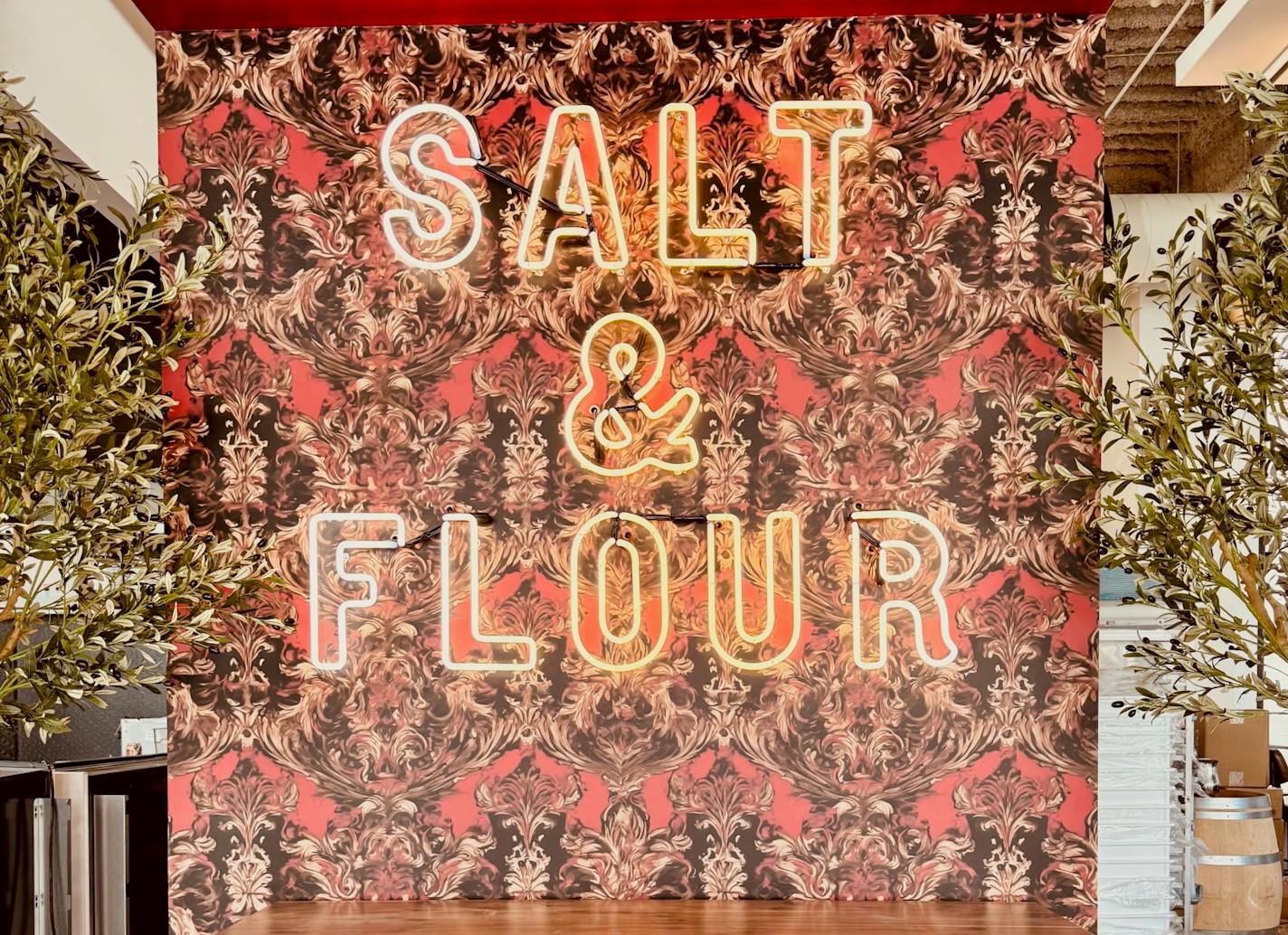 Salt and Flour's neon sign in front of a red and black wallpapered entry wall.