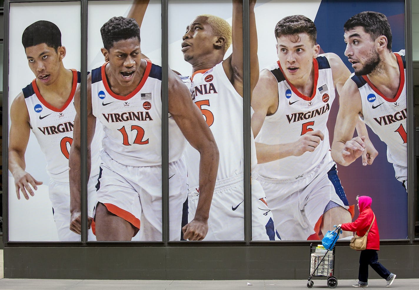 A pedestrian made her way by giant-sized posters of Final Four players near 7th Street and Marquette Avenue on the windows of the IDS Center, Monday, April 1, 2019 in Minneapolis, MN.