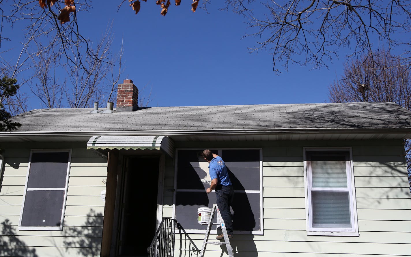 Tim Korby, of Korby's Handyman Services, applied the glue preparing to install the vinyl coverings onto the boarded up windows on this home. ] (KYNDELL HARKNESS/STAR TRIBUNE) kyndell.harkness@startribune.com At a forfeited home in Minneapolis Min., Thursday, March 31, 2014. Hennepin county installed the vinyl covering for the boarded up windows and door it has purchased from Michigan-based Home Illusions.