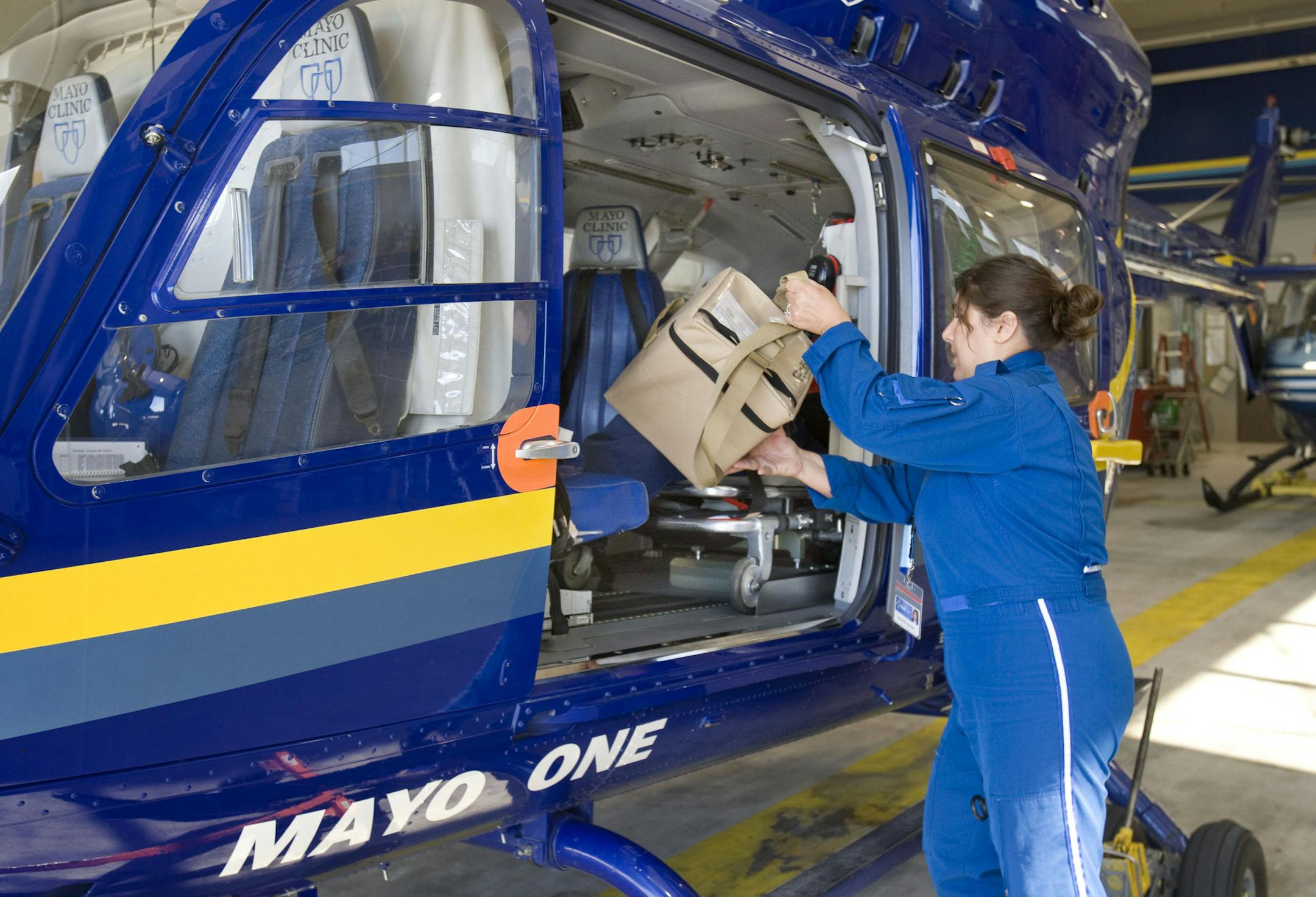 ADVANCE FOR USE SATURDAY, OCT. 11 - In this photo taken on July 22, 2014, Mayo One paramedic Jessica Fite loads a refrigerated supply of plasma and blood onto the Mayo One helicopter in Rochester, Minn. The temperature-controlled blood is brought along on every run. Mayo flew it's first patient by helicopter 30 years ago. (AP Photo/The Rochester Post-Bulletin, Jerry Olson)