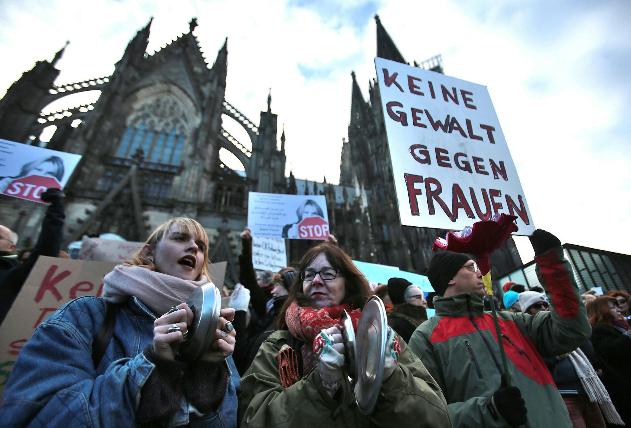 Demonstrators protest against racism and sexism in the wake of the sexual assaults on New Year's Eve, outside the cathedral in Cologne, Germany, Saturday Jan. 9, 2016. Poster at right reads: No violence against women. After the sexual assaults around Cologne's main station on New Year's Eve, various groups have called for demonstrations on Saturday. (Oliver Berg/dpa via AP) ORG XMIT: MIN2016011418021659