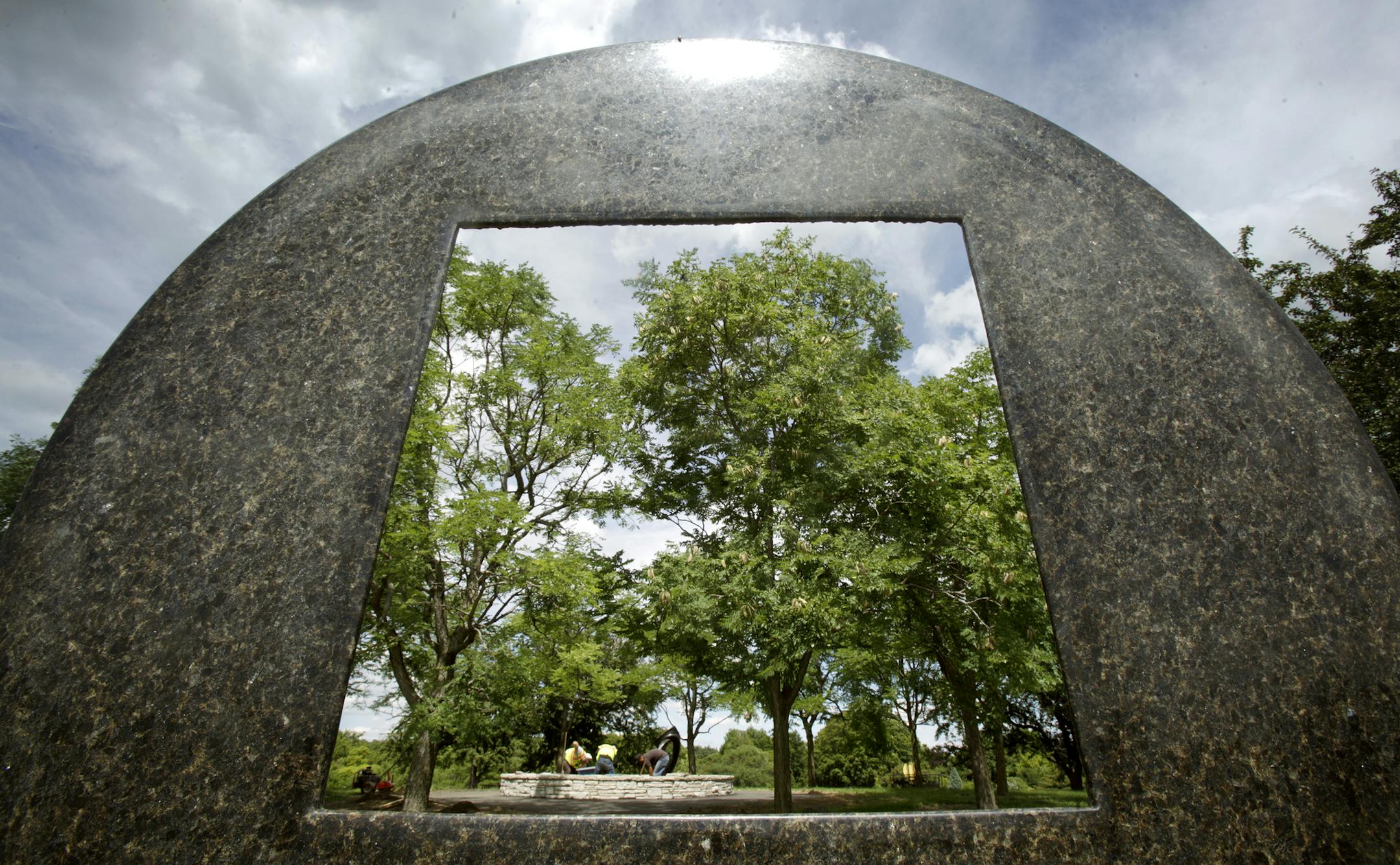 Looking thru "DISC SPIRAL" 2000 by Jesus Bautista Moroles as workers plant around a sculpture called "Blutenmotiv" by Rudulf Belling at the University of Minnesota Landscape Arboretum in Chanhassen, MN on July 29, 2013. ] JOELKOYAMA&#x201a;&#xc4;&#xa2;joel koyama@startribune One by one, sculptures have been hauled onto a grassy knoll during the past several months at the University of Minnesota Landscape Arboretum in Chanhassen. The world-class collection of 22 sculptures, donated by a Wayzata a