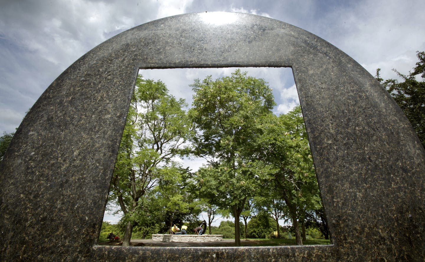 Looking thru "DISC SPIRAL" 2000 by Jesus Bautista Moroles as workers plant around a sculpture called "Blutenmotiv" by Rudulf Belling at the University of Minnesota Landscape Arboretum in Chanhassen, MN on July 29, 2013. ] JOELKOYAMA&#x201a;&#xc4;&#xa2;joel koyama@startribune One by one, sculptures have been hauled onto a grassy knoll during the past several months at the University of Minnesota Landscape Arboretum in Chanhassen. The world-class collection of 22 sculptures, donated by a Wayzata a