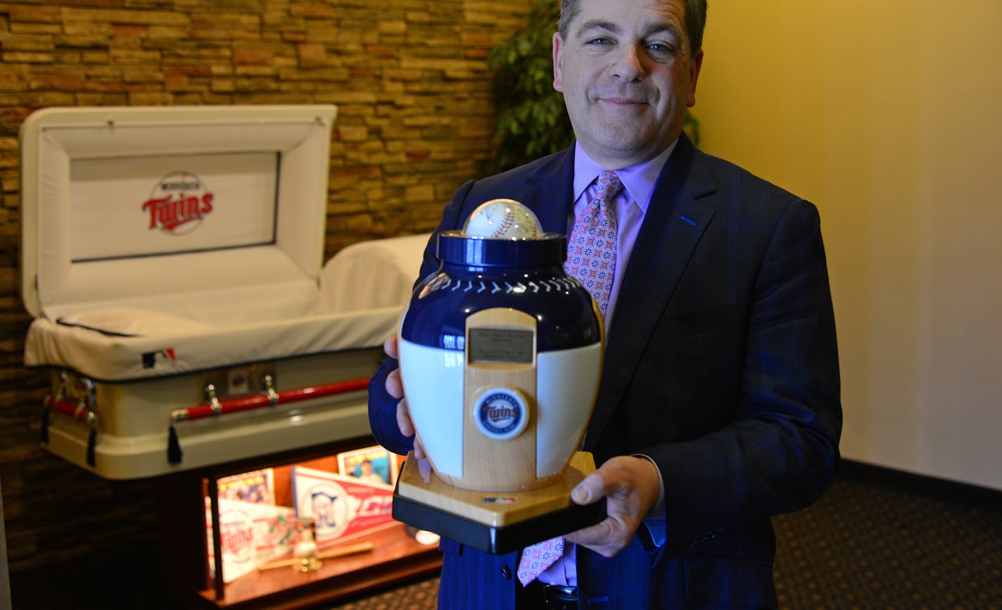 Scott Mueller of Mueller Memorial funeral home held a Twins themed urn with the Twins themed casket in the background both are sanctioned by MLB. .Elaine Arnold, 84, was a lifelong Twins fan, spending decades yelling at Killebrew, Carew, Puckett and Mauer in person and at the TV. When she died, her family was delighted to find a baseball-shaped urn with a Twins logo resting on a home plate-shaped pedestal to store her remains. She could have opted for a logo-emblazoned casket, thanks to new offe