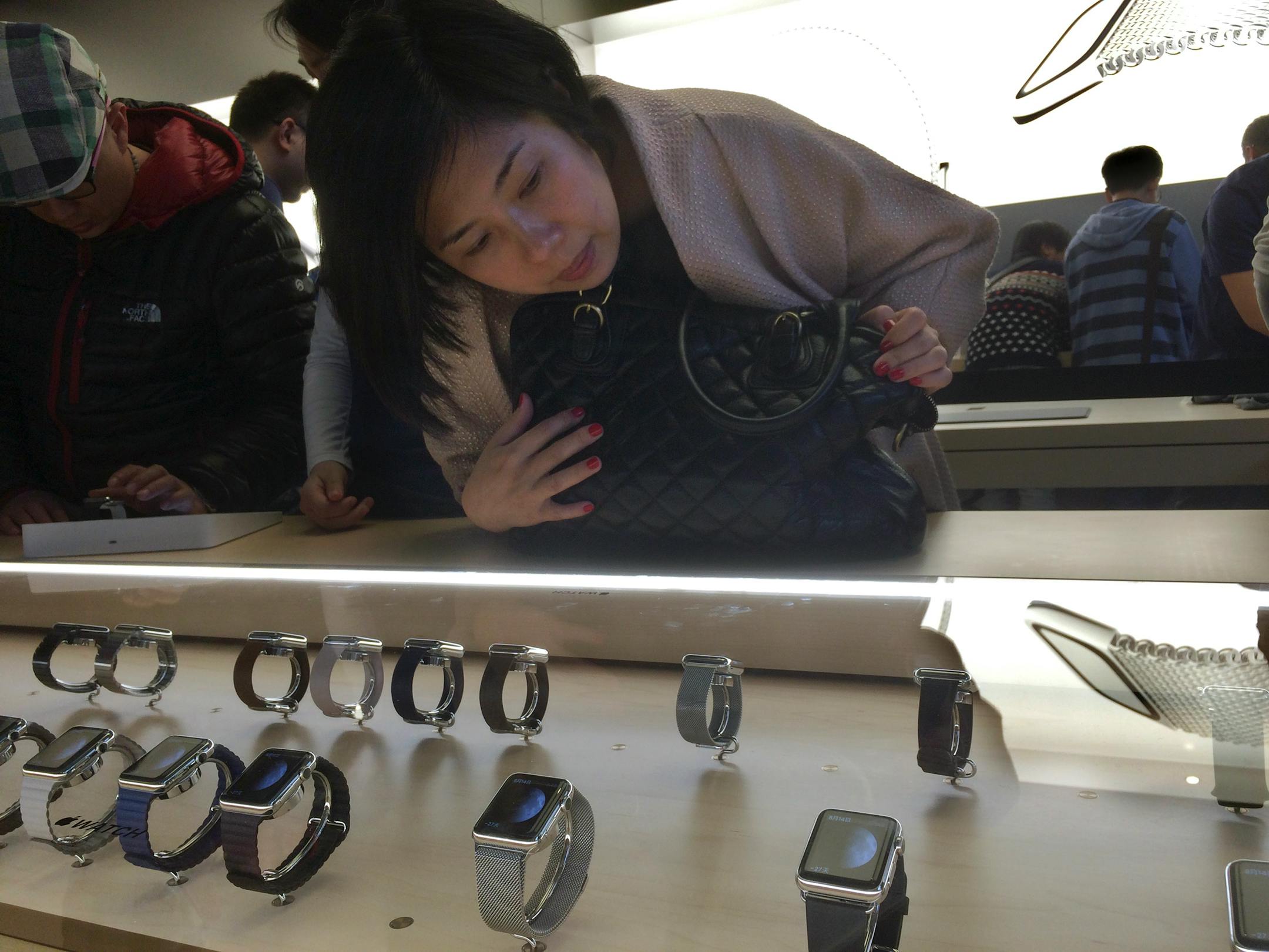 A customer takes a close look at Apple Watches on display in a glass case at an Apple retail store in Beijing, Friday, April 10, 2015. From Beijing to Paris to San Francisco, the Apple Watch made its debut Friday. Customers were invited to try them on in stores and order them online. China was among countries where the watch had its global debut Friday, reflecting the country's fast-growing status as one of Apple's most important markets. (AP Photo/Ng Han Guan)