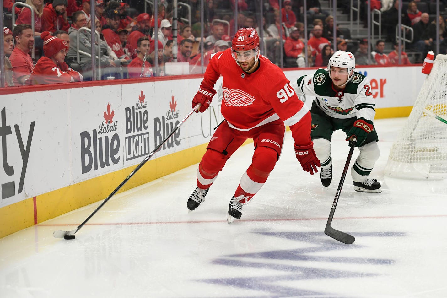 Detroit Red Wings' Joe Veleno, left, skates with the puck in front of Minnesota Wild's Calen Addison during the second period of an NHL hockey game, Saturday, Oct. 29, 2022, in Detroit. (AP Photo/Jose Juarez)