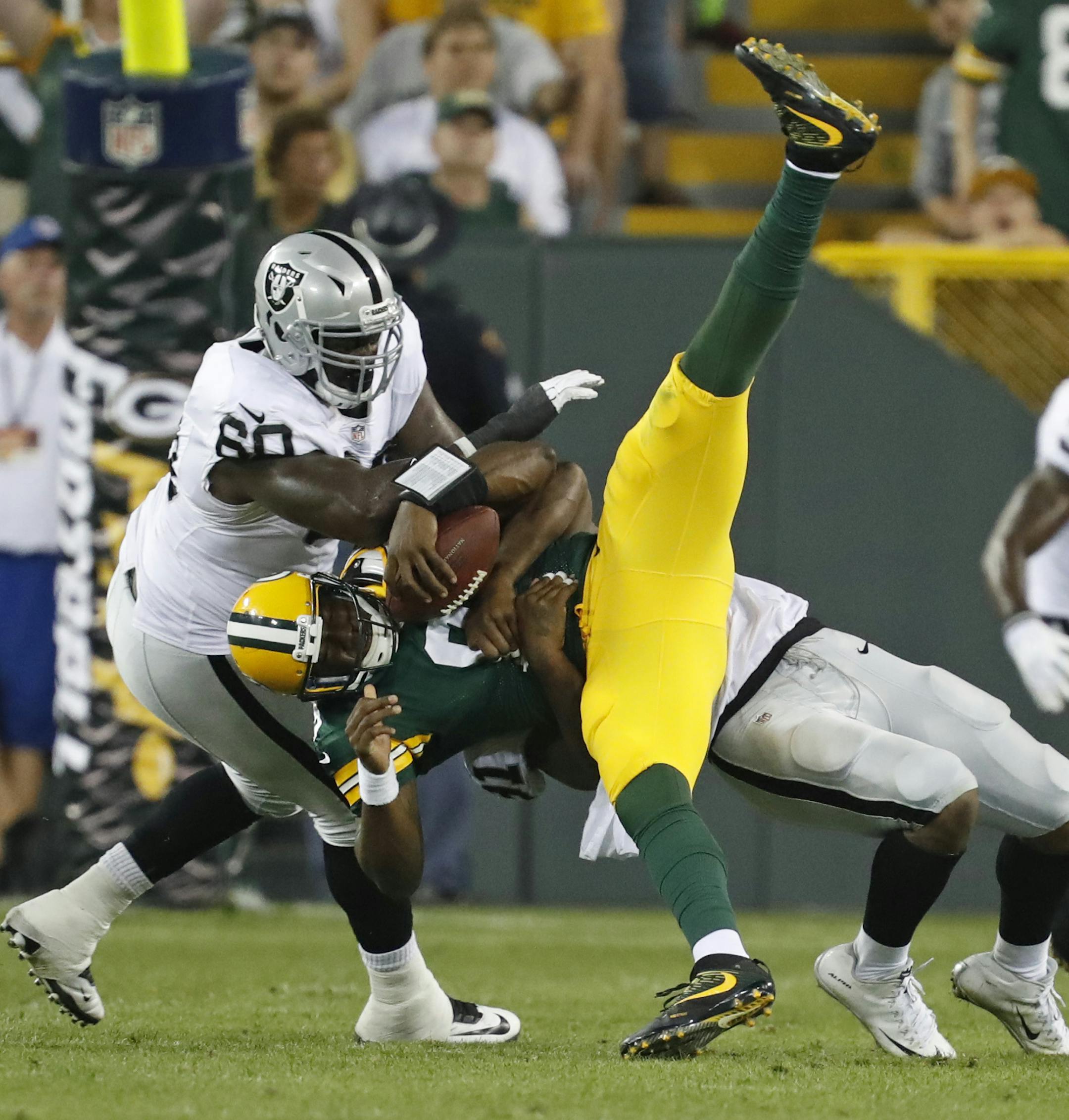 Oakland Raiders defensive tackle Derrick Lott (60) and linebacker Shilique Calhoun sack Green Bay Packers quarterback Marquise Williams, center, during the second half of an NFL preseason football game in Green Bay, Wis., Thursday, Aug. 18, 2016. (AP Photo/Matt Ludtke)