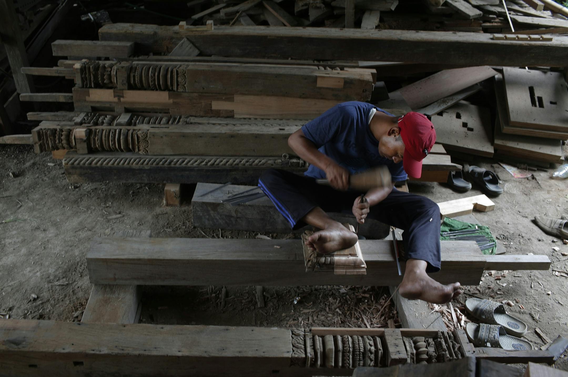 In this photo taken Wednesday, July 19, 2017, a woodworker from the Newar ethnic community carves wood in Lalitput, Nepal. In the rubble of Nepal's 2015 earthquake, a team of dedicated woodworkers is finding inspiration to recreate what was lost. Centuries-old Char Narayan and Hari Shankara temples were completely destroyed by the massive April 2015 earthquake that shook the Himalayan nation, killing nearly 9,000 people. The temples were the jewel of the Patar Durbar Square, which is thronged by