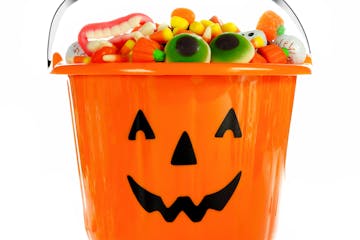 Halloween Jack o Lantern candy collector filled with candy over a white background