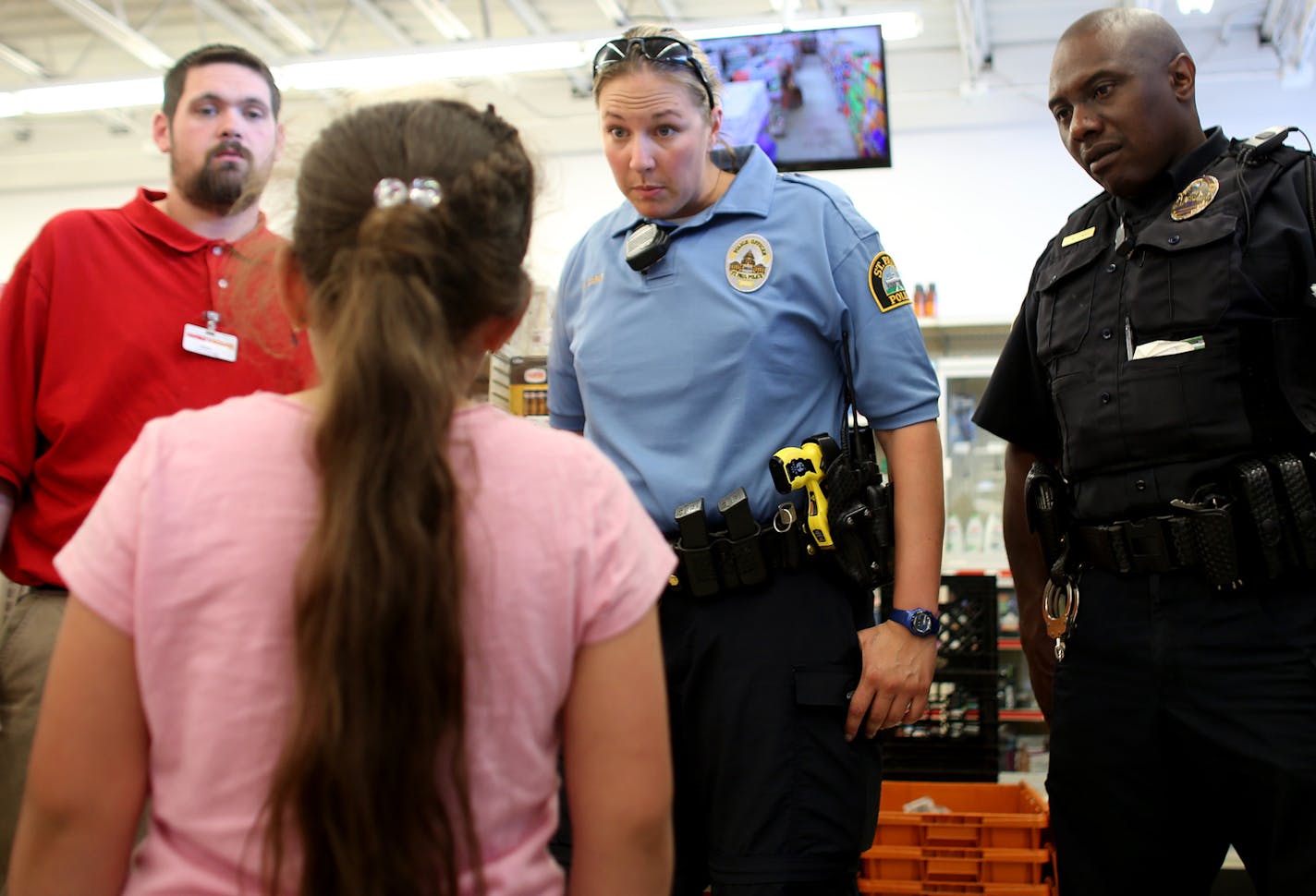 Alyssa Cortes, 7, listened as Officers Nicole Carle and Leonard Mitchell talked about not taking things that don't belong to you. Cortes had pocketed a pack of gum and her mother asked for the officers to talk to her. ] (KYNDELL HARKNESS/STAR TRIBUNE) kyndell.harkness@startribune.com Shadowing officers Mitchell and Carle as they walk in the Payne Avenue area in St Paul Min., Friday, May 22, 2015.