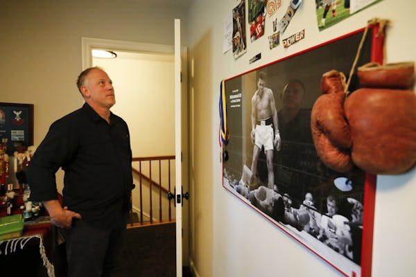 Don Amorosi paused to look at poster of Muhammad Ali, boxing gloves and photos of other athletes including Tom Brady that hang inside his son Archer's