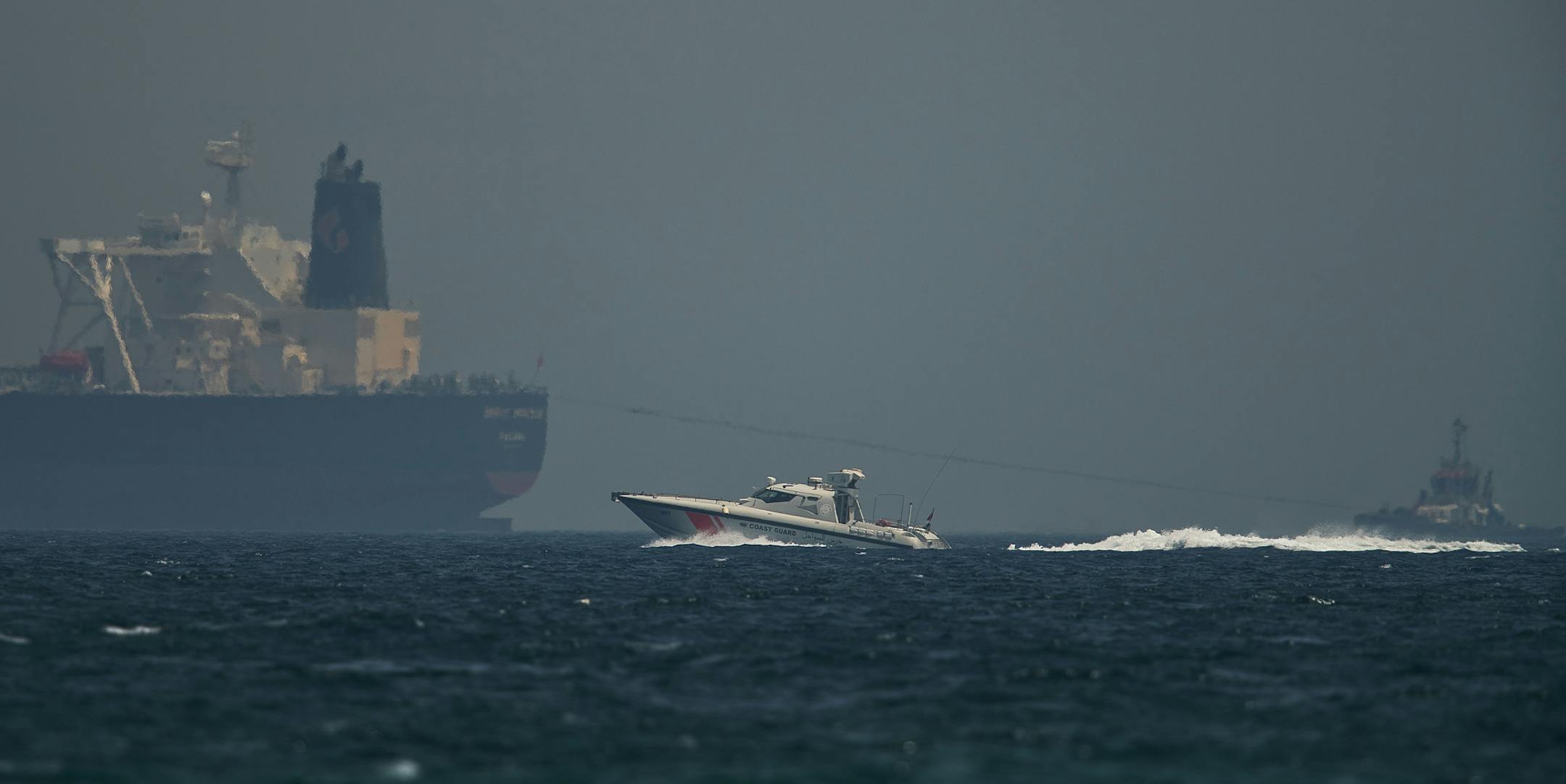 An Emirati coast guard vessel passes an oil tanker off the coast of Fujairah, United Arab Emirates, Monday, May 13, 2019. Saudi Arabia said Monday two of its oil tankers were sabotaged off the coast of the United Arab Emirates near Fujairah in attacks that caused "significant damage" to the vessels, one of them as it was en route to pick up Saudi oil to take to the United States. (AP Photo/Jon Gambrell) ORG XMIT: XJG101