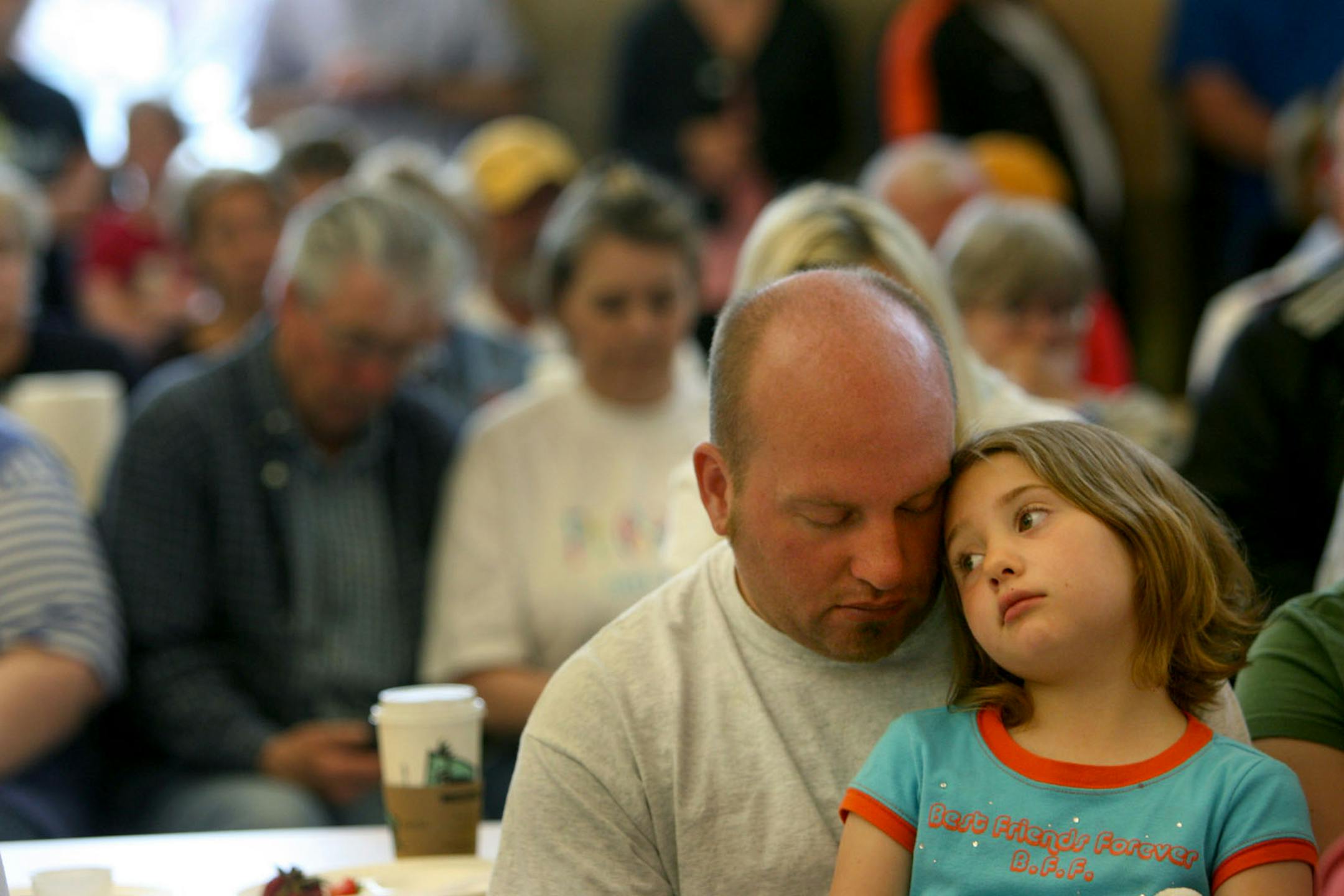 Steve Anderson, with his 6-year-old daughter Rebekah, bowed his head after hearing that there was a fatality after a tornado ripped through their subdivision in Hugo.