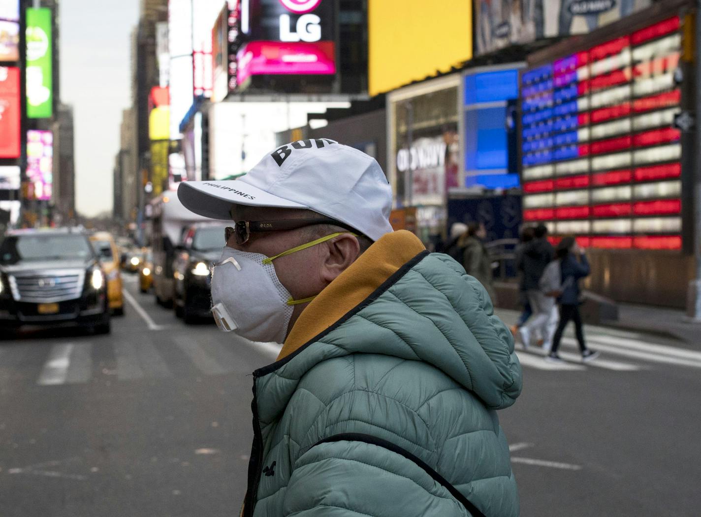 A man wears a face mask as he walks through Times Square in New York, March 2, 2020. The Trump administration said on Monday, March 2, that nearly a million tests could be administered for the coronavirus in the United States by the end of this week, a significant escalation of screening as the American death toll reached six and U.S. infections topped 100. (Dave Sanders/The New York Times)