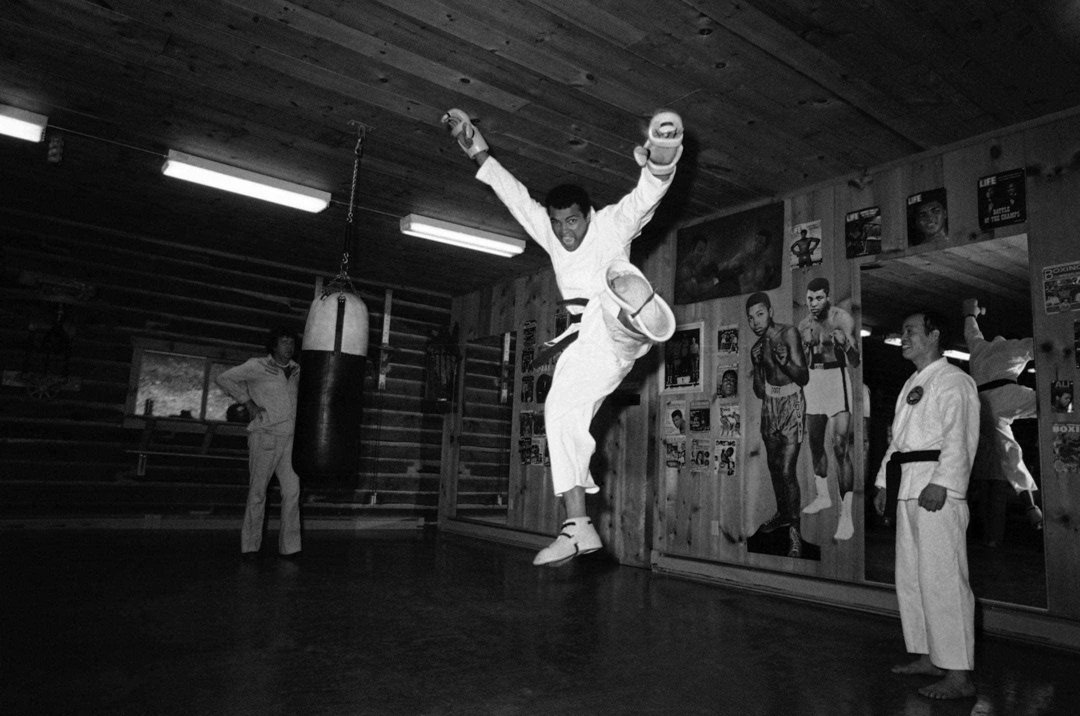 Muhammad Ali takes to the air as he receives a few lessons in karate at his Deer Park, Pa. training camp, Aug. 13, 1975. Ali is getting the instructions from an 8th degree karate black belt from Korea. He is wearing special karate gloves and boots. (AP Photo/Ron Frehm) ORG XMIT: APHS284721
