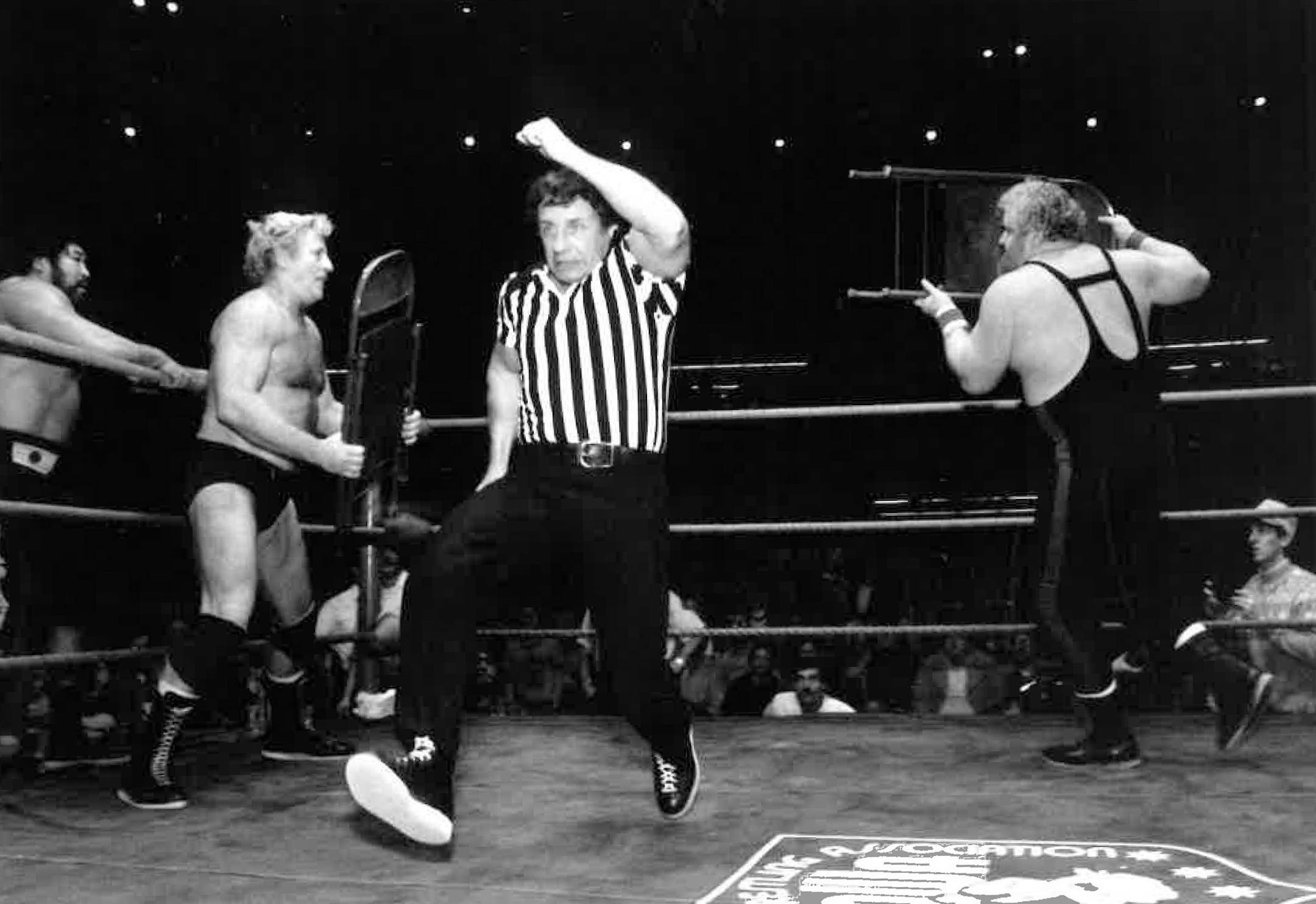 Referee and trainer Eddie Sharkey ran from a chair fight with Nick Bockwinkle, left, and Larry Hennig as a Mr. Saito tag team member waited in the wings at left.