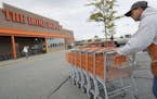 FILE - In this file photo made Oct. 6, 2009, employee John Abou Nasr pushes shopping carts in the parking lot of a Home Depot in Methuen, Mass. Home D