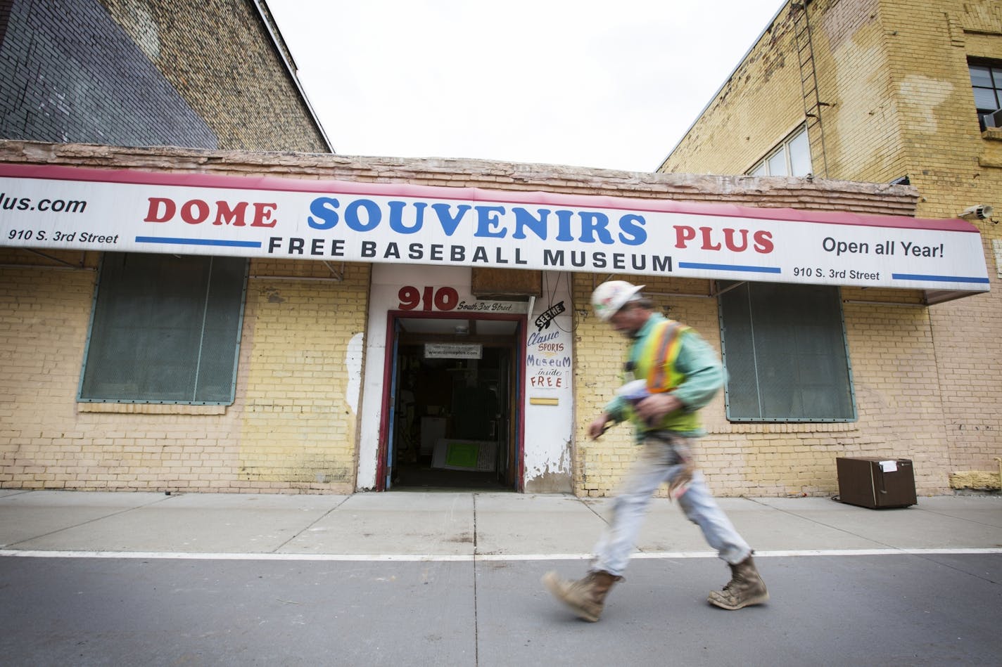 A construction worker walks past Dome Souvenirs, which is surrounded by large construction projects, in downtown Minneapolis on Friday, August 28, 2015.