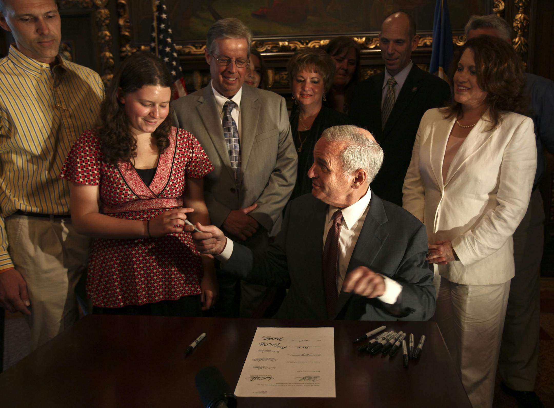 Gov. Mark Dayton handed Kayla Meyer a pen he used after signing a mock bill which hopes to raise awareness about concussions in young people.