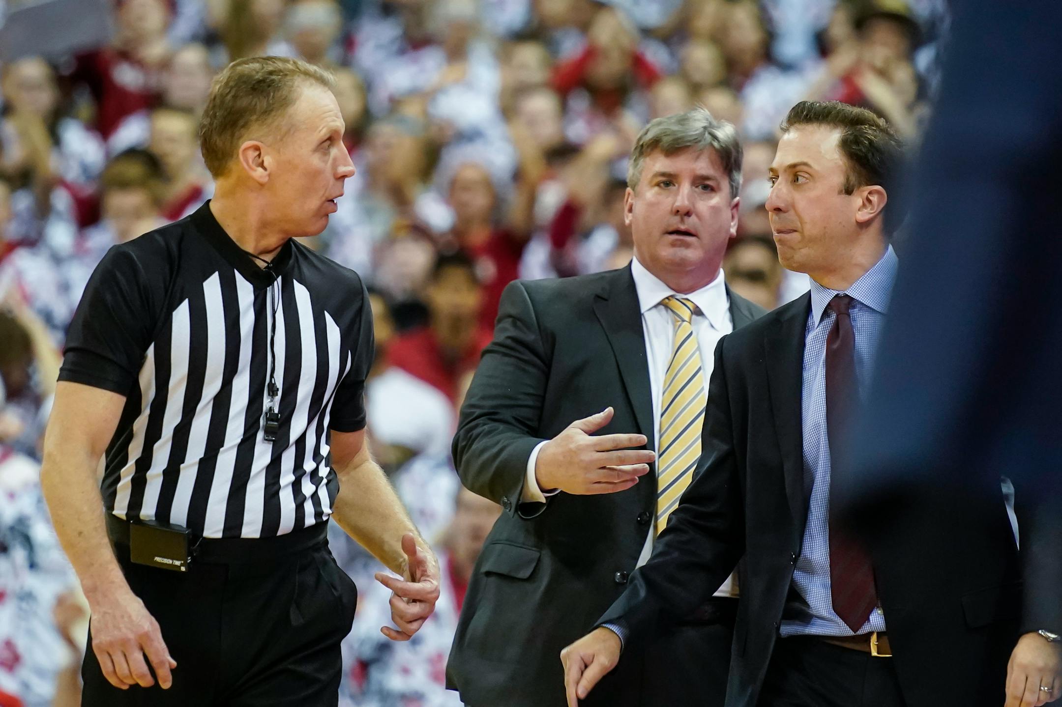 Gophers coach Richard Pitino, right, argued a call with official Mike Eades during the second half of Wisconsin's 71-69 victory in Madison on Sunday. Behind Pitino is assistant coach Ed Conroy.