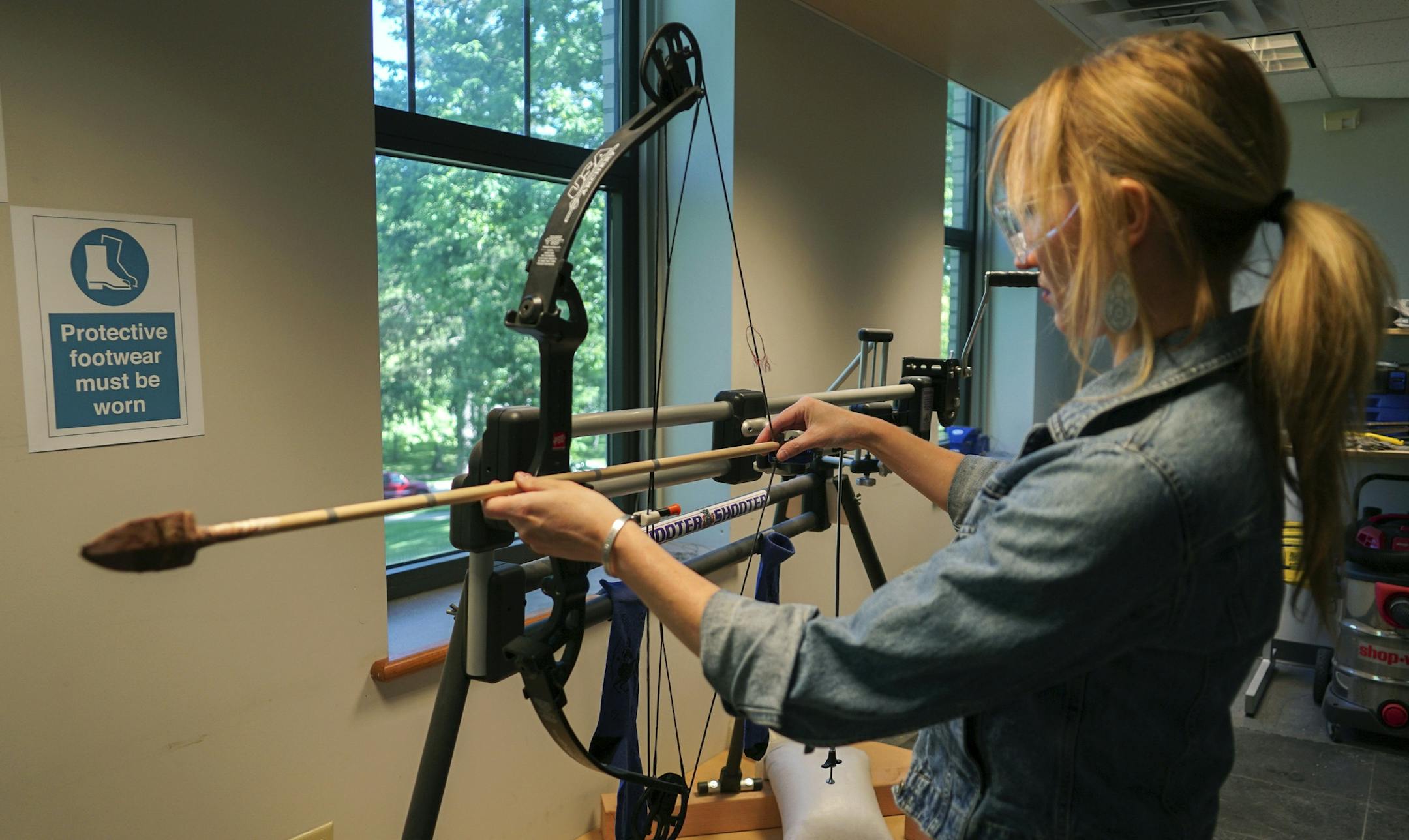 In this June 1, 2017, photo, Michelle Bebber, a PhD archeology student at Kent State University, loads a bow with a recreated ancient arrow in Kent, Ohio. Bebber conducts research at a newly-opened laboratory which makes replicas of ancient arrows, knives, and pottery to be shot, crushed, and smashed. It's allowing researchers to learn about engineering techniques of the first native Americans without destroying priceless genuine relics in the process. (AP Photo/Dake Kang)