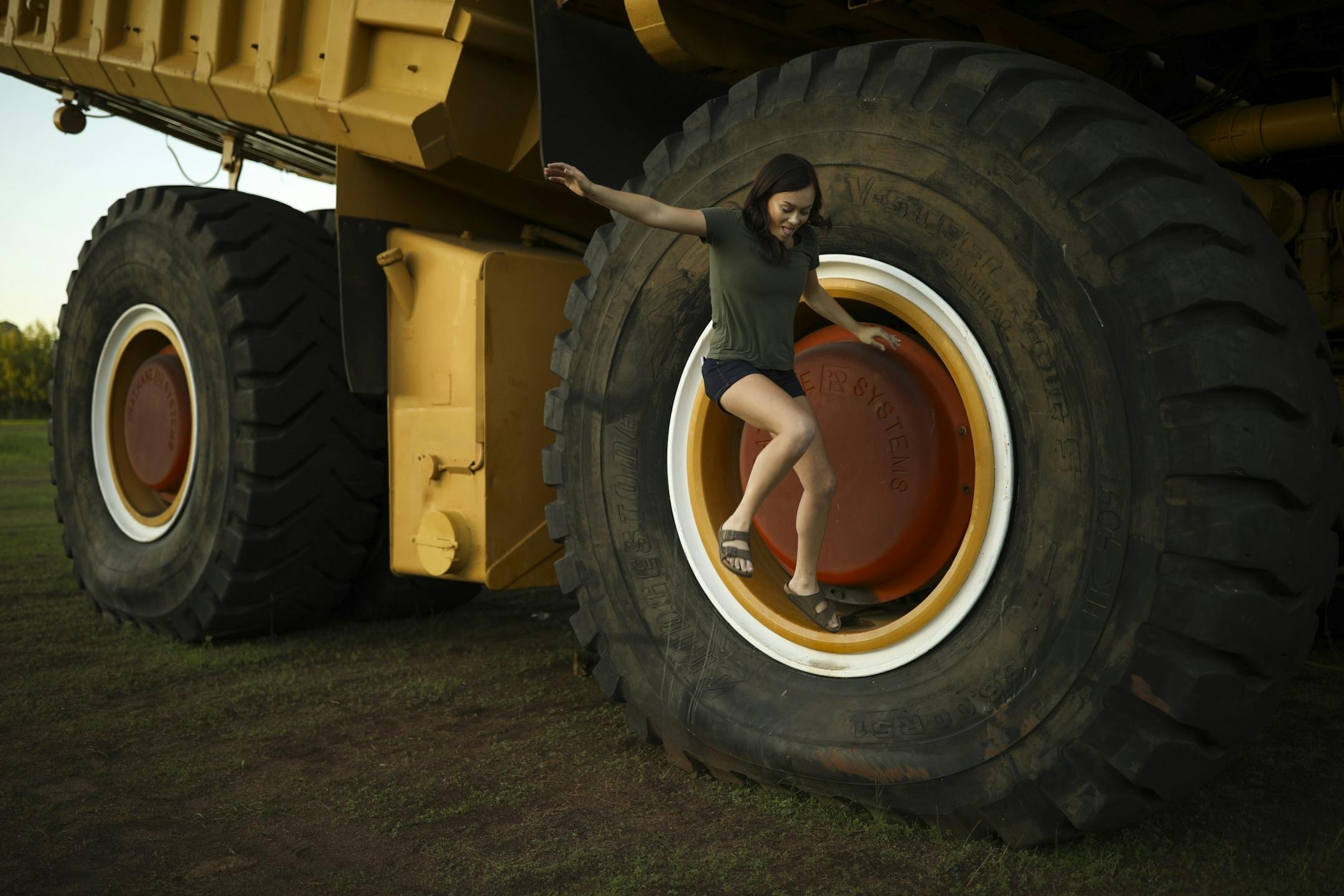 Hayley Bocht, 19, a waitress at Boomtown Brewery & Woodfire Grill with a giant dump truck that that was moved from the Hull-Rust-Mahoning Mine View ahead of the mine's current expansion.