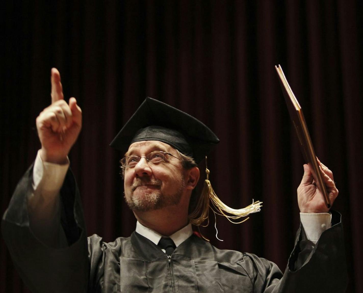 After two decades of taking college classes, Bob Alberti, held his diploma and pointed to family members in the crowd after earning his diploma during a ceremony for the University of Minnesota's College of Continuing Education at Ted Mann Concert Hall in Minneapolis, MN, Saturday, May 5, 2012.