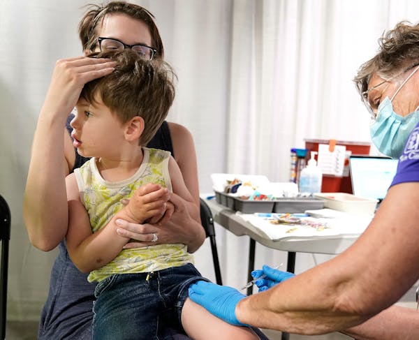 Juliana Biederman of Lino Lakes shielded the eyes of her son Sully, 3, as he received his first COVID-19 vaccine at the Mall of America vaccination si