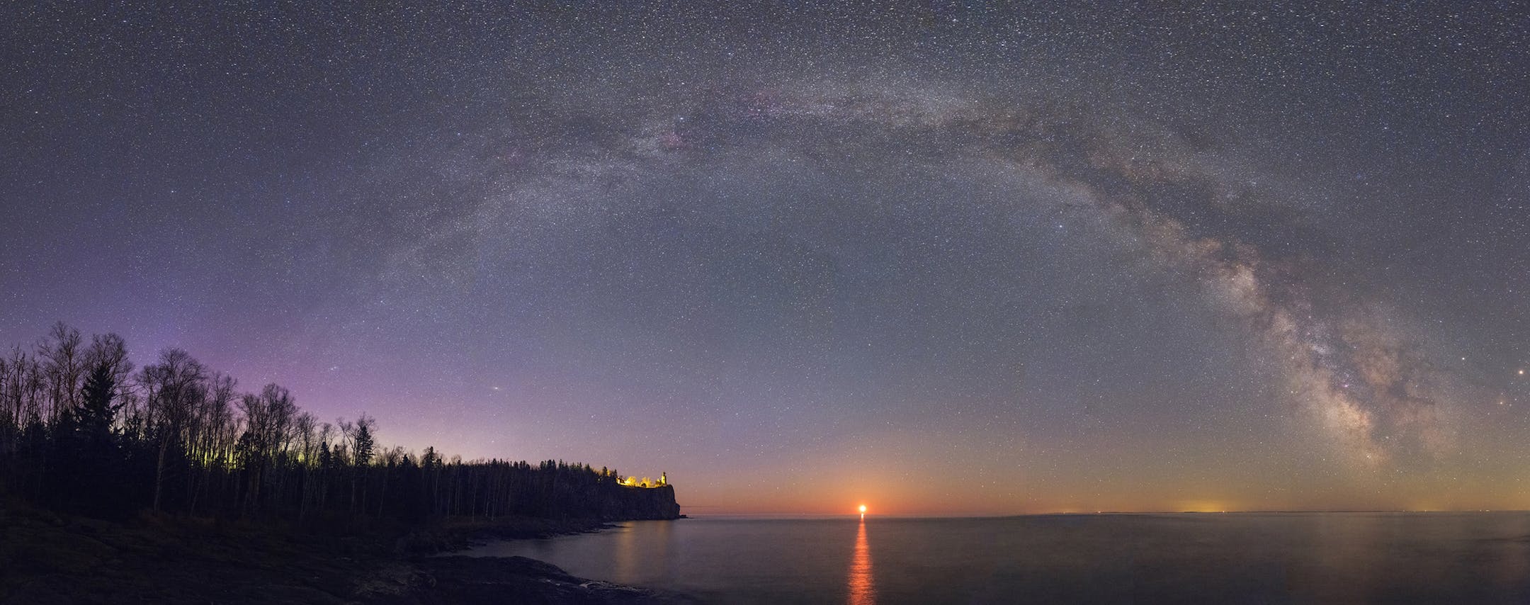 ONE TIME USE. The glittering central band of the Milky Way galaxy arches majestically over famous Split Rock Lighthouse on the north shore of Lake Superior. Many notable stars, planets, constellations, star clusters, gas nebulae, and even the Andromeda galaxy are visible in this 26-image, 180-degree panoramic view that spans from north to south. Made around 4:00 am in early May, it was timed to include the rising crescent moon (not the sun!) &#xf1; along with a faint display of the Aurora Boreal
