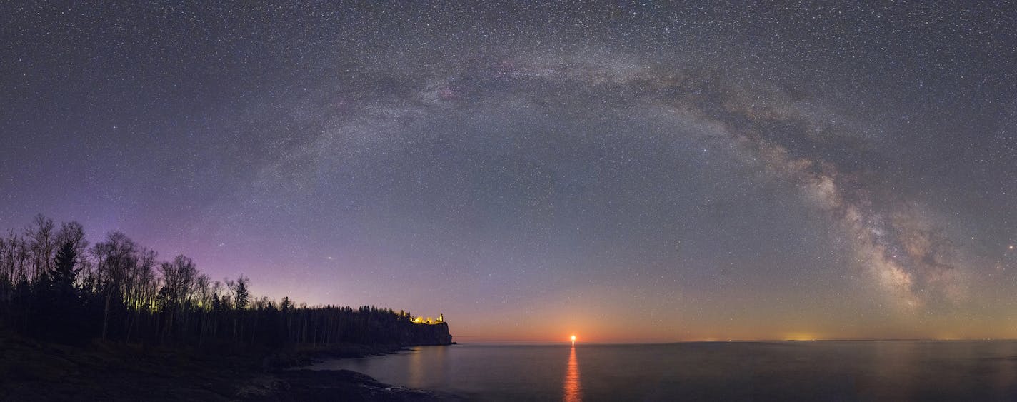 ONE TIME USE. The glittering central band of the Milky Way galaxy arches majestically over famous Split Rock Lighthouse on the north shore of Lake Superior. Many notable stars, planets, constellations, star clusters, gas nebulae, and even the Andromeda galaxy are visible in this 26-image, 180-degree panoramic view that spans from north to south. Made around 4:00 am in early May, it was timed to include the rising crescent moon (not the sun!) &#xf1; along with a faint display of the Aurora Boreal