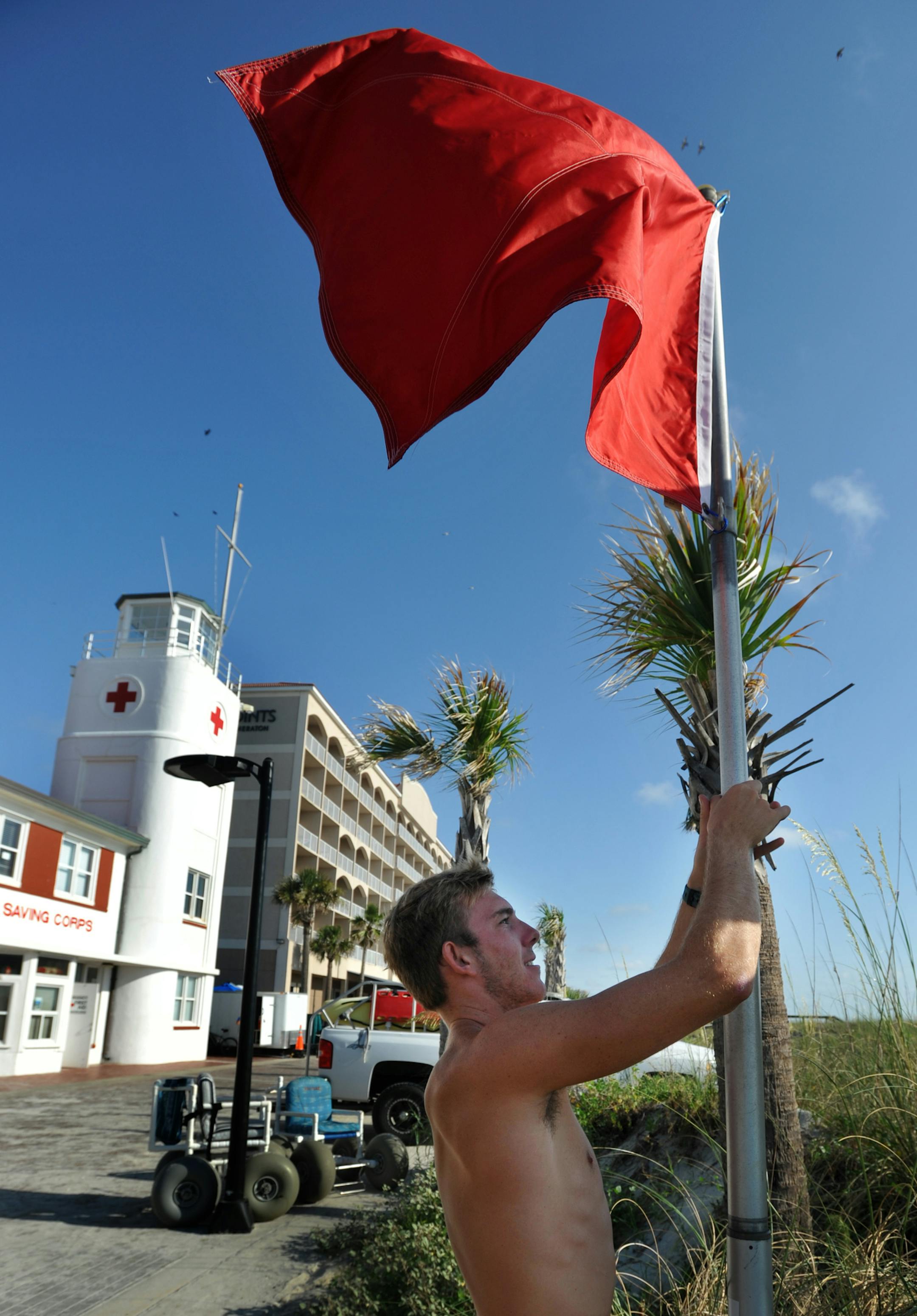 07/01/14--Lifeguard Travis Blakeslee raises the red high hazard flag, Tuesday morning, July 1, 2014, at the Red Cross lifeguard station in Jacksonville Beach, Fla. The red flag was raised in anticipation of rip currents and high waves from a tropical depression forming off Florida's coast that is expected to become Tropical Storm Arthur and pass to the east of Florida. (AP Photo/The Florida Times-Union, Will Dickey) ORG XMIT: MIN2014070212282427