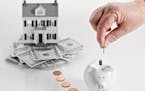 A conceptual image showing a reverse mortgage with a home sitting on a pile of money and a hand dropping coins slowly in a piggy bank. istock photo