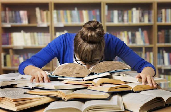 Student Studying Hard Exam and Sleeping on Books, Tired Girl Read Difficult Book in Library
istock