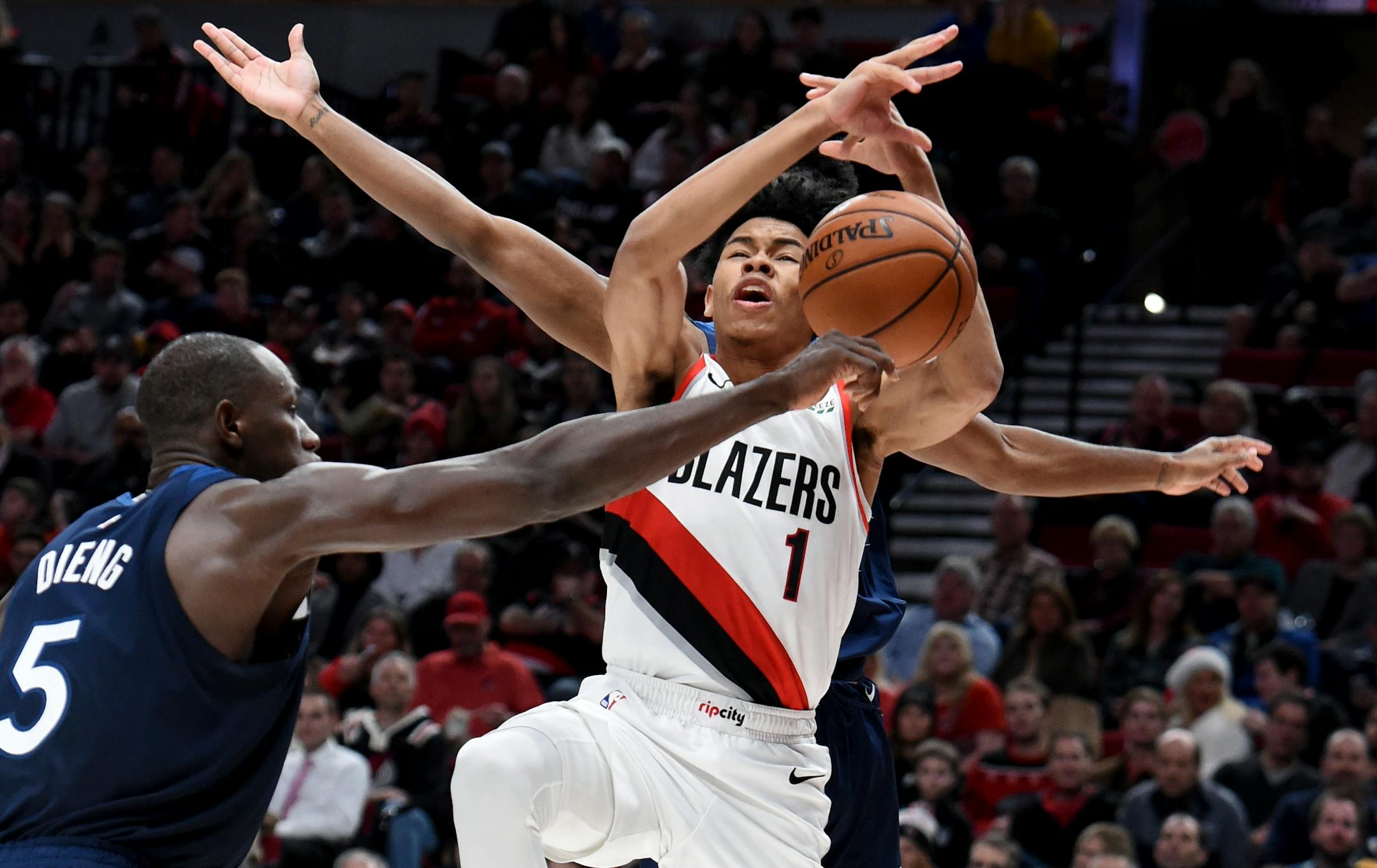 Minnesota Timberwolves center Gorgui Dieng, left, knocks the ball away from Portland Trail Blazers guard Anfernee Simons during the second half of an NBA basketball game in Portland, Ore., Saturday, Dec. 21, 2019. The Blazers won 113-106. (AP Photo/Steve Dykes)