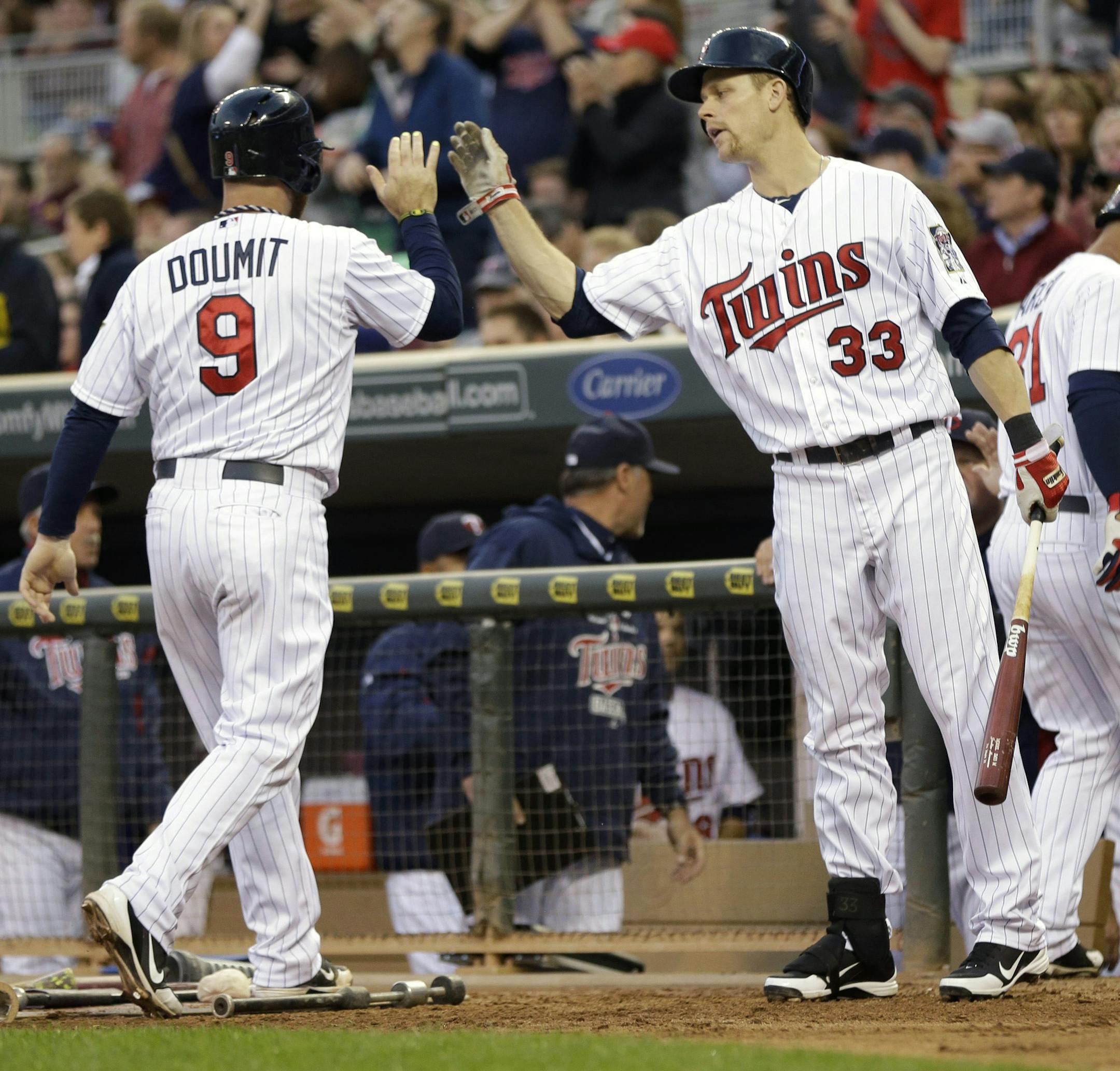 Minnesota Twins catcher Ryan Doumit, left, is congratulated by teammate Justin Morneau, center, as he and Oswaldo Arcia, right, score on a two-run single by Joe Mauer off Baltimore Orioles pitcher Jason Hammel in the second inning of a baseball game on Friday, May 10, 2013, in Minneapolis. (AP Photo/Jim Mone)