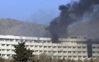 Men try to escape from a balcony of the Intercontinental Hotel after an attack in Kabul, Afghanistan, Sunday, Jan. 21, 2018. Gunmen stormed the hotel 