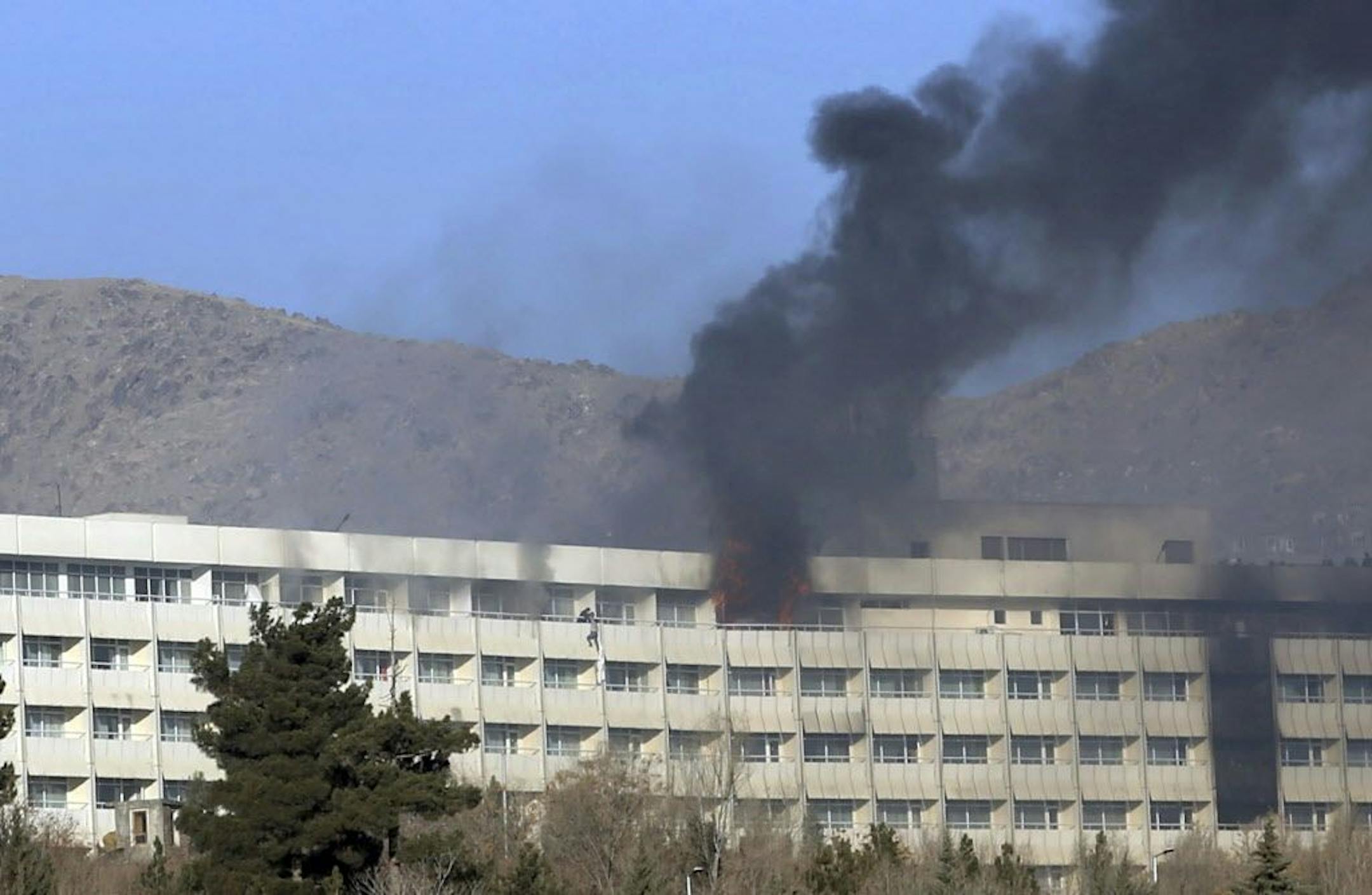 Men try to escape from a balcony of the Intercontinental Hotel after an attack in Kabul, Afghanistan, Sunday, Jan. 21, 2018. Gunmen stormed the hotel and sett off a 12-hour gun battle with security forces that continued into Sunday morning, as frantic guests tried to escape from fourth and fifth-floor windows.