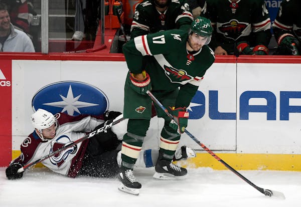 Colorado Avalanche's Sven Andrighetto (10), of Switzerland, crashes into the boards as Minnesota Wild's Marcus Foligno (17) takes the puck during the 