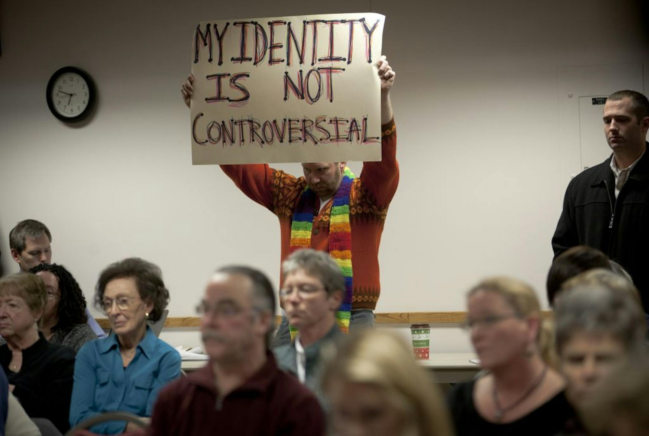 Blaine High School teacher Kendrick Davies, center, with sign, was in the crowd at Monday's Anoka-Hennepin school board meeting.