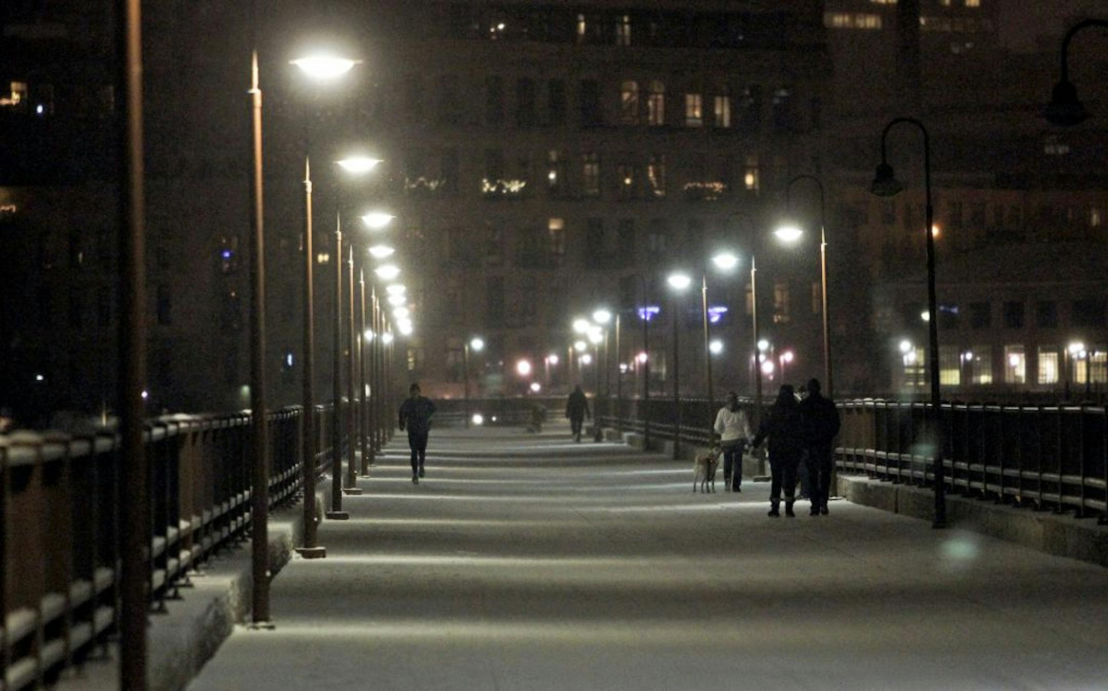 Pedestrians and a runner share the freshly blanketed Stone Arch Bridge during what may turn out to be the Twin Cities metro's first significant snowfall of the season Friday, Dec. 7, 2012, in Minneapolis, MN.
