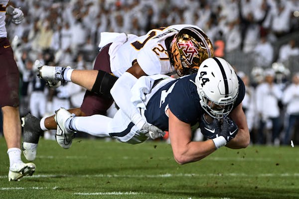 Penn State tight end Tyler Warren dives past Gophers defensive back Tyler Nubin to score a first-half touchdown Saturday in State College