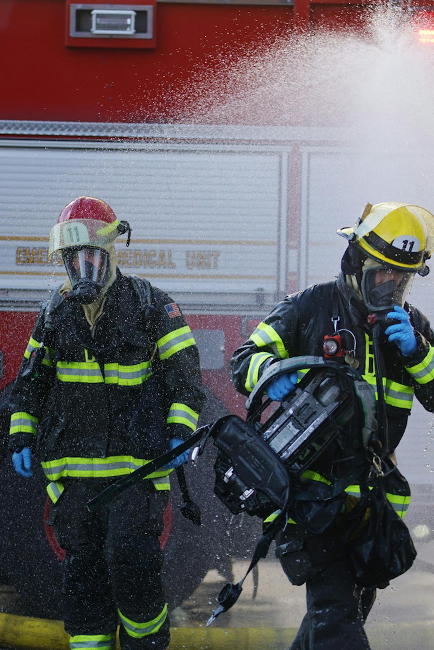 Two Minneapolis firefighters went under a water spray to help clear their suits of any hazardous substances after responding Tuesday to a Dinkytown-area residential building.