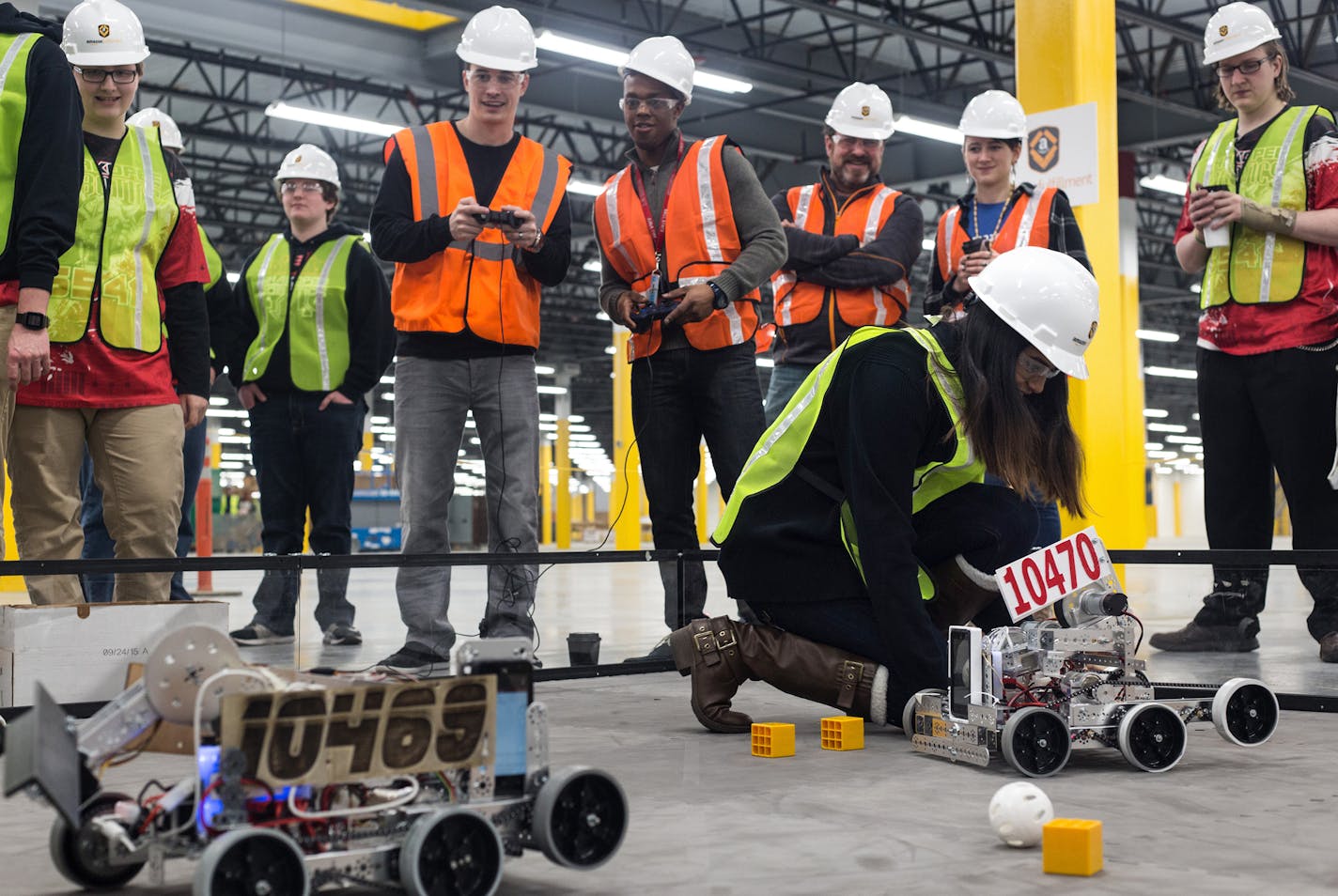 Members of Shakopee Robotics, the Shakopee Senior High School's Robotoic Team, and Amazong employees play with the team's personally designed robots in the not yet open Amazon Shakopee fulfillment center Friday morning. Amazon awarded the robotics team 10,000 dollars. ] Elizabeth Brumley special to the Star Tribune