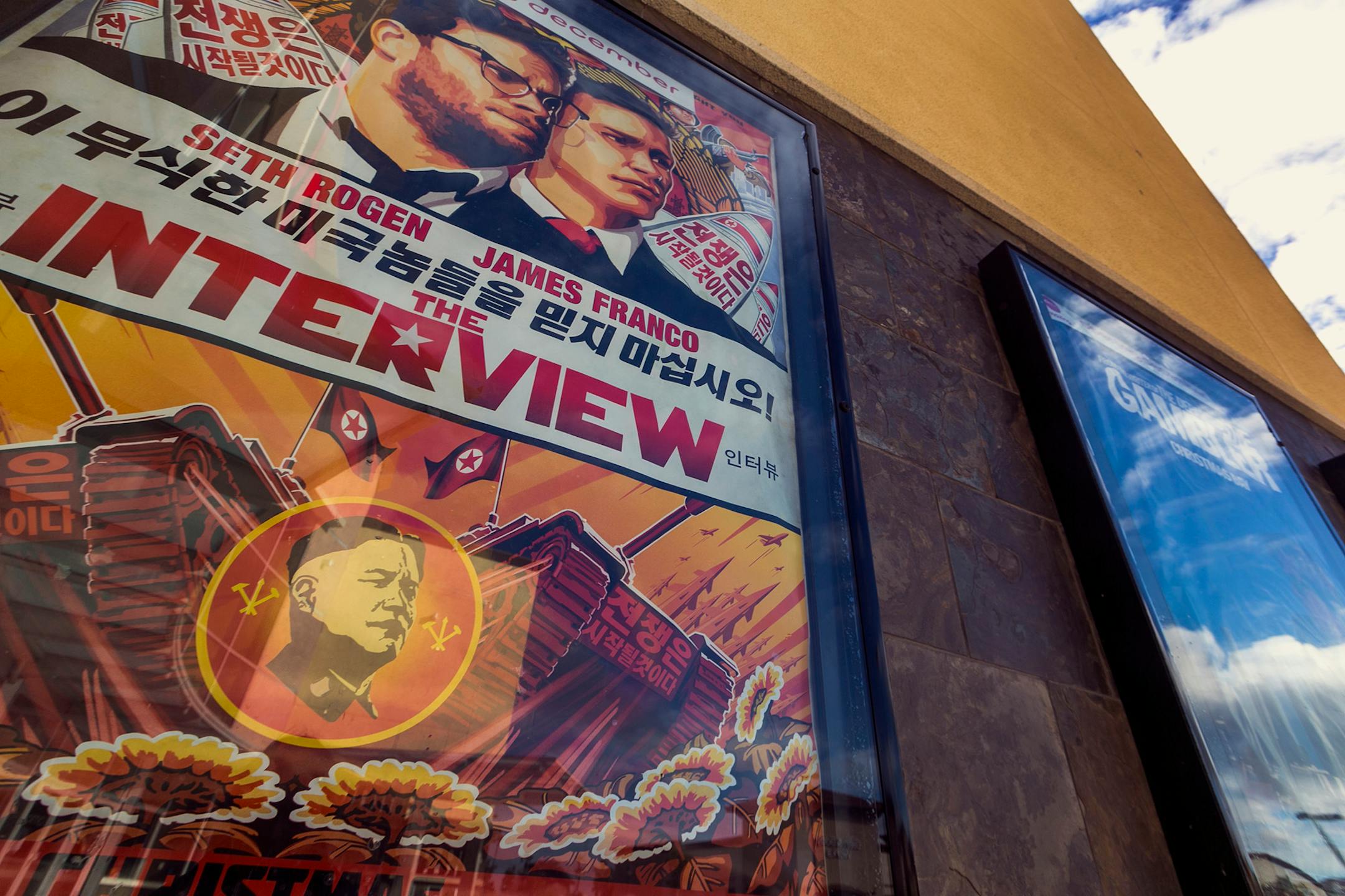 A movie poster for the movie "The Interview" is displayed outside the AMC Glendora 12 movie theater Wednesday, Dec. 17, 2014, in Glendora, Calif. The fallout from the Sony Pictures Entertainment hack that began four weeks ago exploded Tuesday after the shadowy group calling themselves Guardians of Peace escalated their attack beyond corporate espionage and threatened moviegoers with violence reminiscent of the terrorist attacks of September 11, 2001. (AP Photo/Damian Dovarganes)