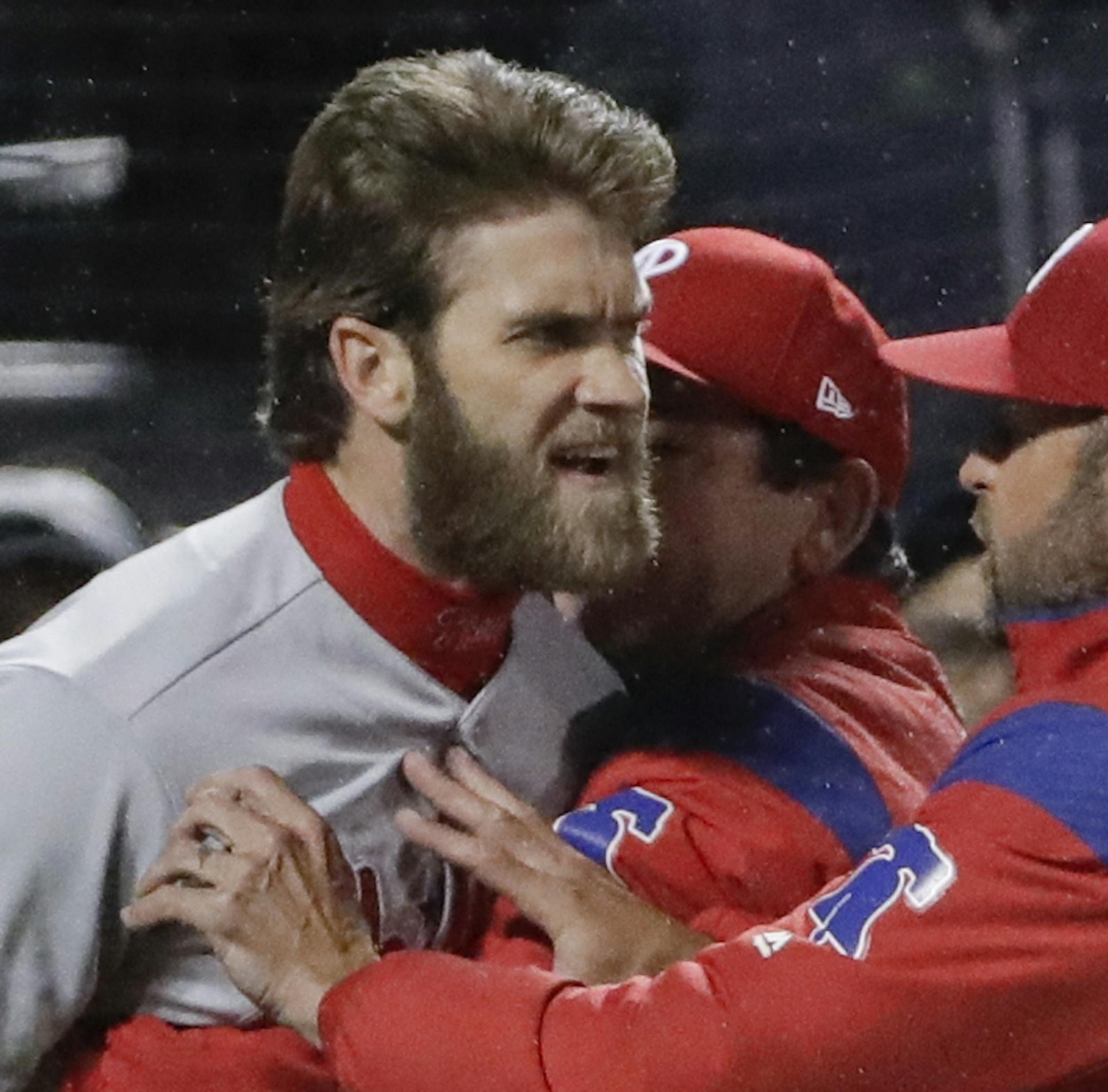 Philadelphia Phillies' Bryce Harper, left, is restrained while arguing with umpire Mark Carlson, right, during the fourth inning of a baseball game against the New York Mets, Monday, April 22, 2019, in New York. (AP Photo/Frank Franklin II)