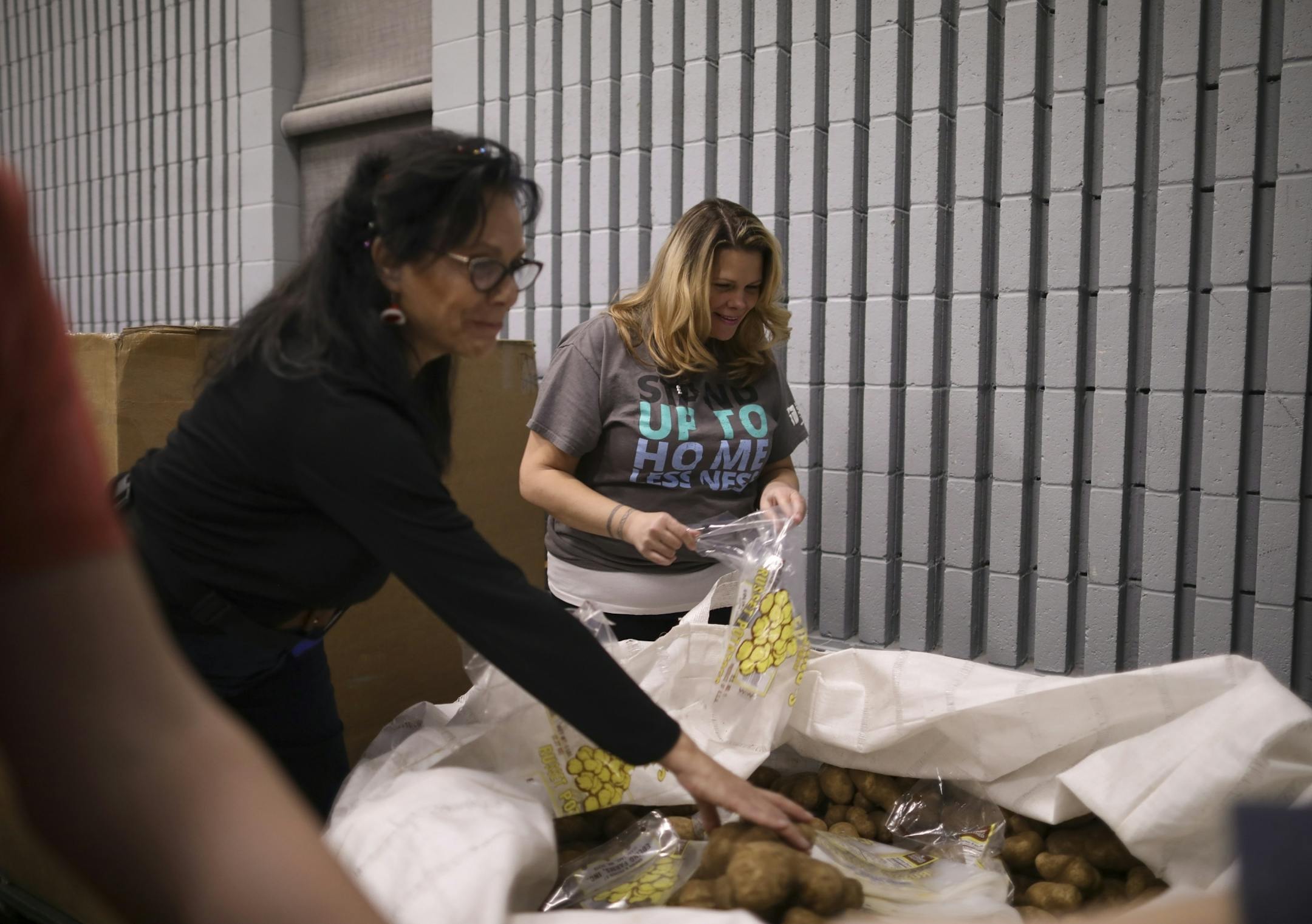 Christy Vasquez bagged potatoes with Lonnie West, left, Monday evening at the Union Gospel Mission.