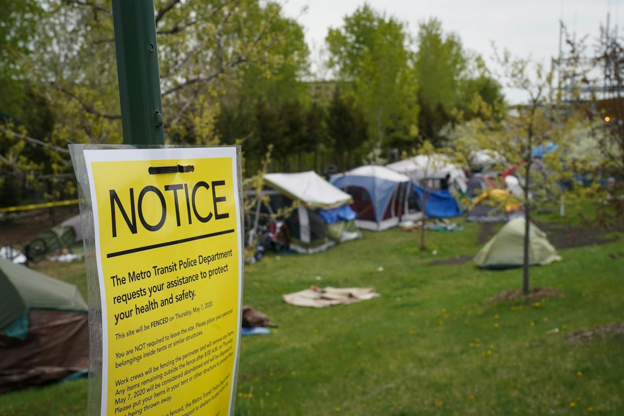 What began in March as a small camp consisting of about a couple dozen homeless adults has now swelled to more than 100 residents in tents. Known as "Camp Quarantine," the fast-growing encampment has raised alarms over the health of the camp residents amid the coronavirus pandemic. In this photo, notices were put up throughout the camp that a perimeter fence will be built around the neighborhood.