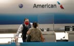 American Airlines ticket agent Henry Gemdron, left, works with a customer at Miami International Airport during the coronavirus pandemic, Wednesday, S